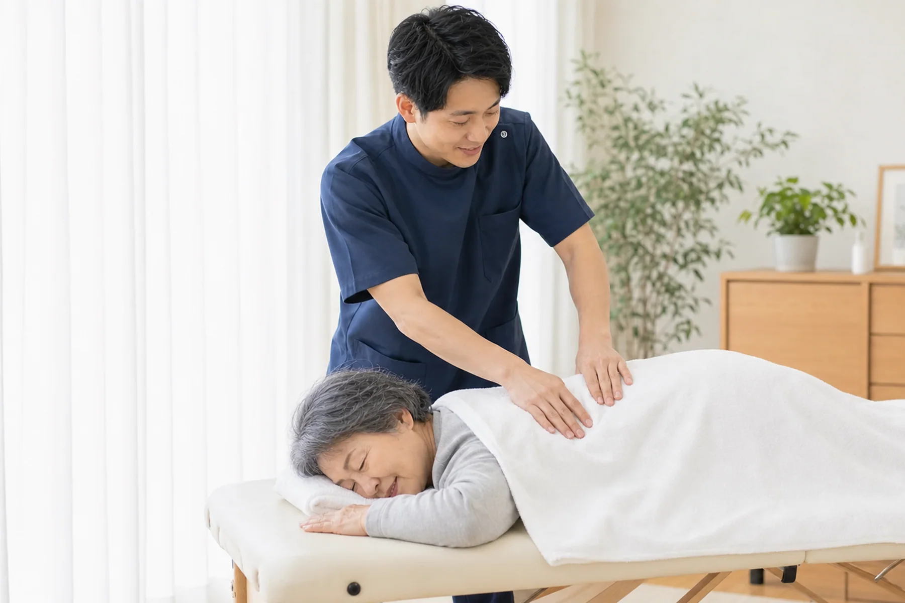 タオルの上から背中のマッサージを行う様子